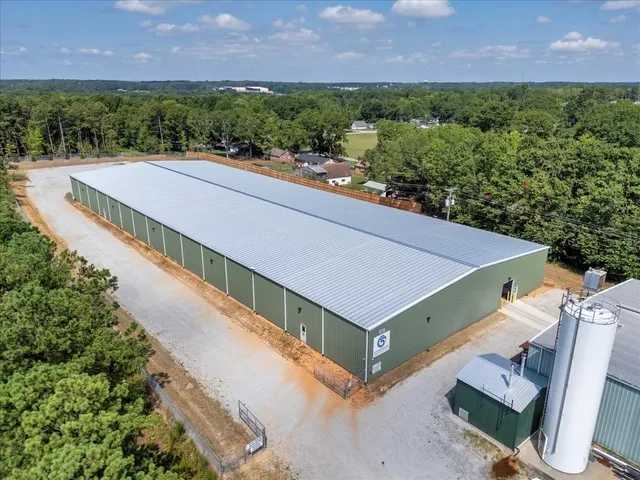 Aerial view of the C5 Warehousing facility highlighting the full length of the warehouse with a metal roof, gated secure perimeter, and surrounding trees.